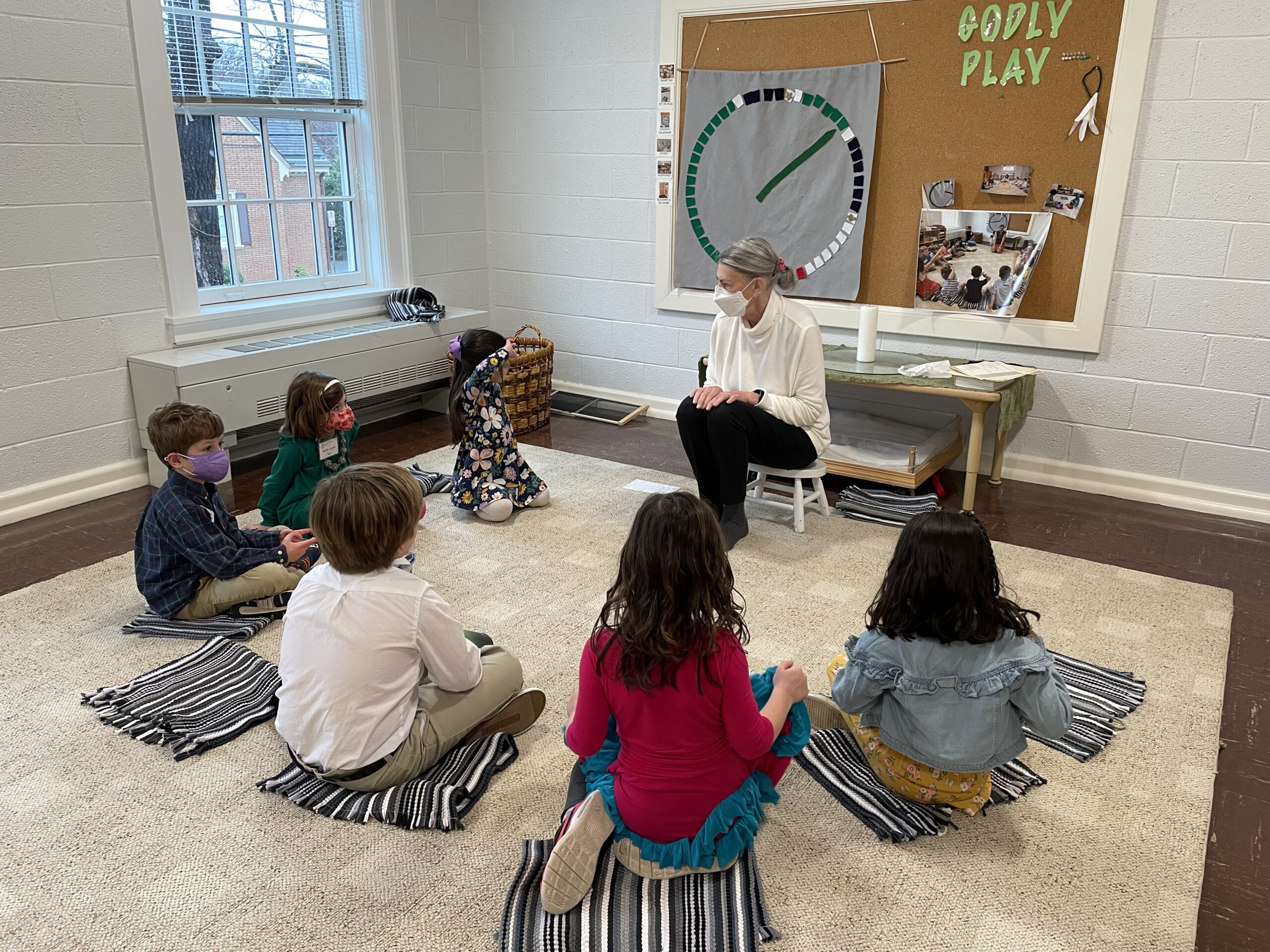 A group of children sitting in a circle on the floor, with their Godly Play teacher sitting with them