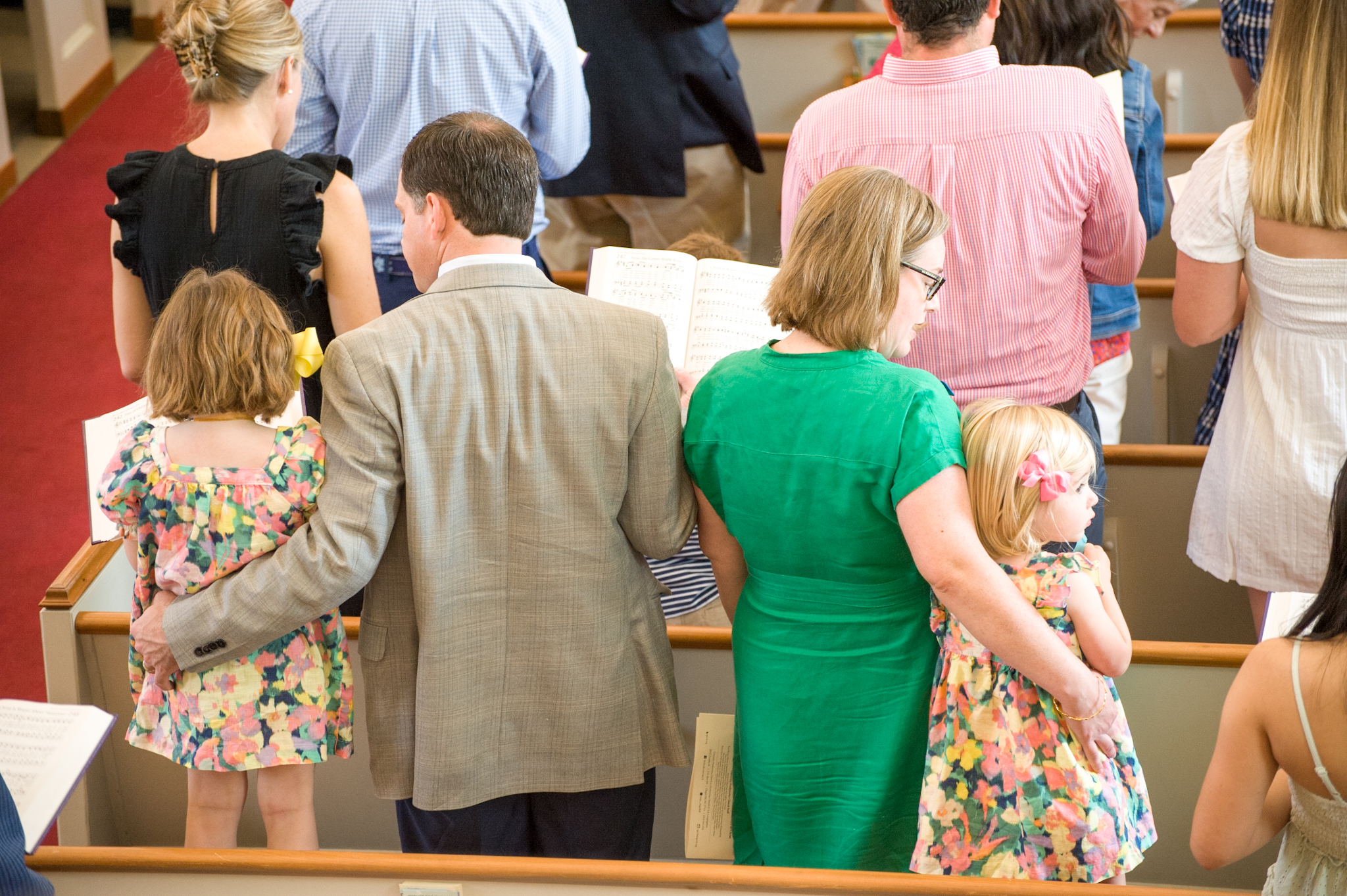 A family with young children worshiping together. They are singing hymns in the sanctuary.